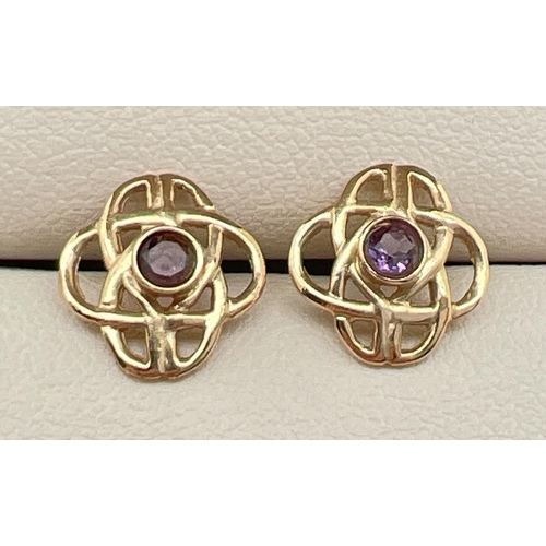 62 - A pair of gold pierced work Celtic design stud earrings set with a small round cut amethysts. Gold m... 