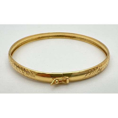 74 - A silver gilt bangle with diamond cut criss cross pattern throughout. Push clasp and safety clip. Ma... 