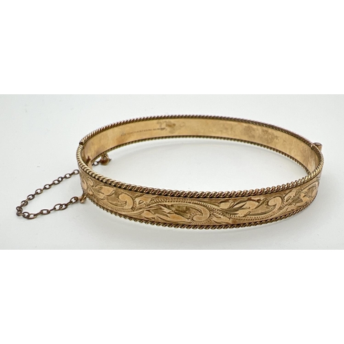 90 - A vintage 9ct rolled gold bangle with floral engraving, push clasp and safety chain. Marks to inside... 