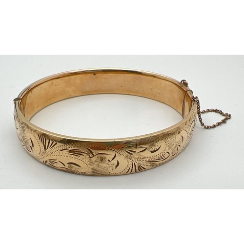 96 - A vintage 9ct rolled gold bangle with half floral engraved pattern, push clasp and safety chain. Gol... 