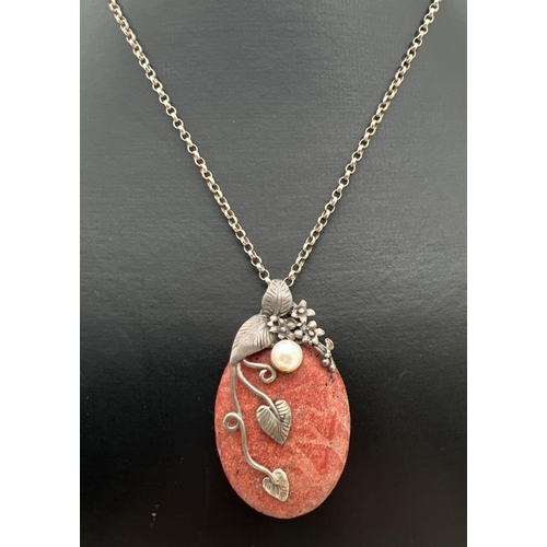 102 - A natural red stone oval shaped pendant with silver floral design overlay, set with a single pearl. ... 