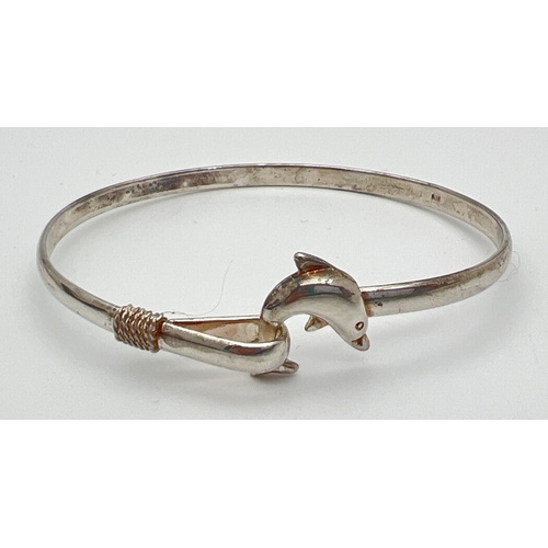 105 - A 925 silver bangle with dolphin detail. Tail of dolphin hooks into loop clasp to secure bracelet. S... 