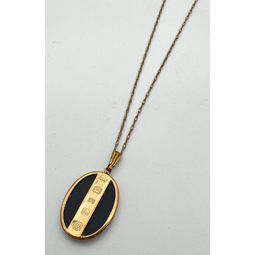 127 - An oval shaped 9ct gold and black onyx pendant with hallmarks to front. On a 19