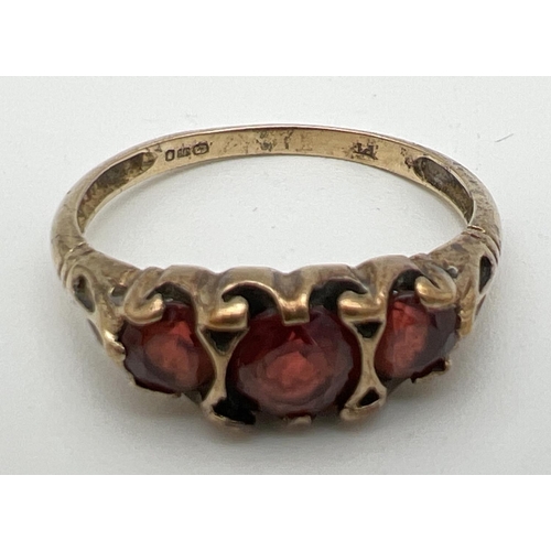 161 - A vintage 9ct gold garnet set trilogy ring with scroll decoration to mount. Size Q. Total weight app... 