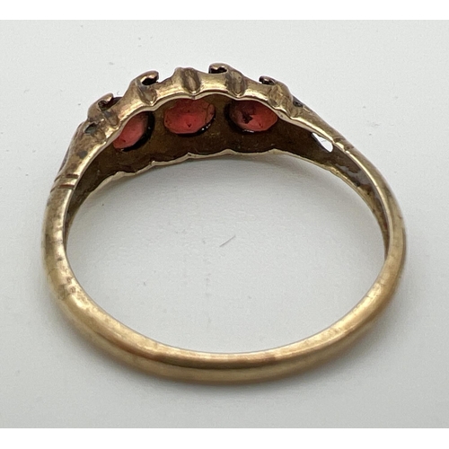 161 - A vintage 9ct gold garnet set trilogy ring with scroll decoration to mount. Size Q. Total weight app... 