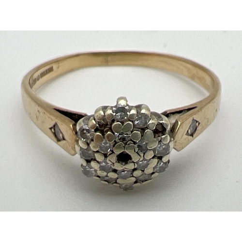 169 - A small 9ct gold diamond cluster ring with a single small diamond set to each shoulder (two small st... 