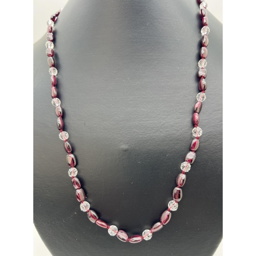 211 - A 20 inch garnet and clear bead necklace with white metal push clasp.