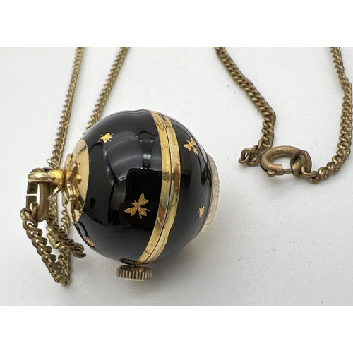 221 - A vintage ball pendant watch by Buler. Gold tone case set with black enamel and gold inset decoratio... 