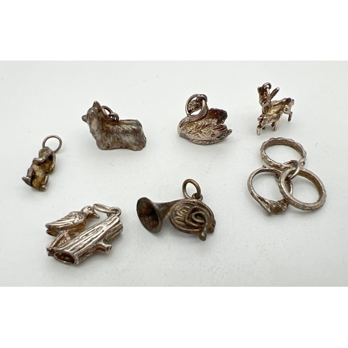 232 - 7 vintage silver and white metal charms. Comprising: triple rings, wise monkey, dog, deer with fawn,... 