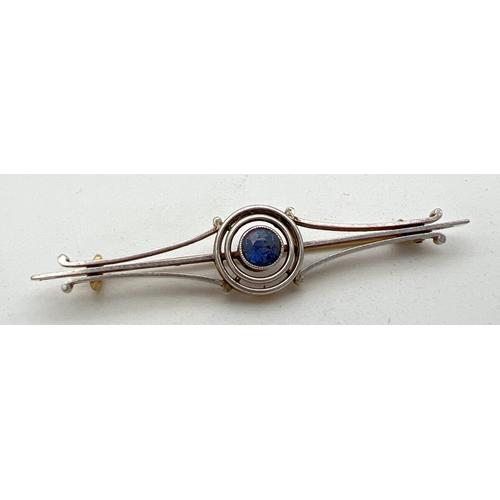 247 - An Art Deco gold bar style brooch with central circular design, set with a round cut sapphire. Engra... 