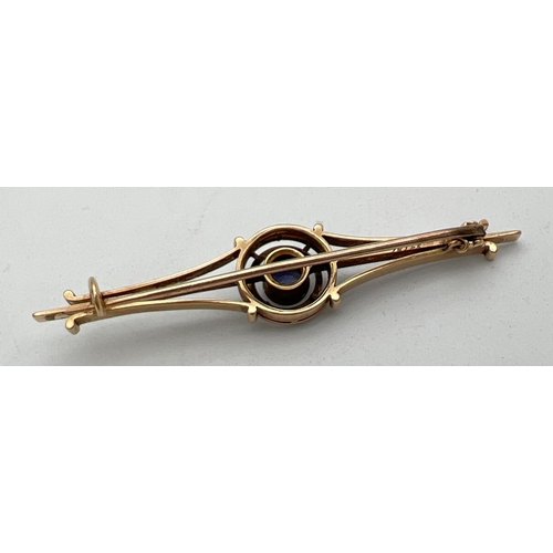 247 - An Art Deco gold bar style brooch with central circular design, set with a round cut sapphire. Engra... 