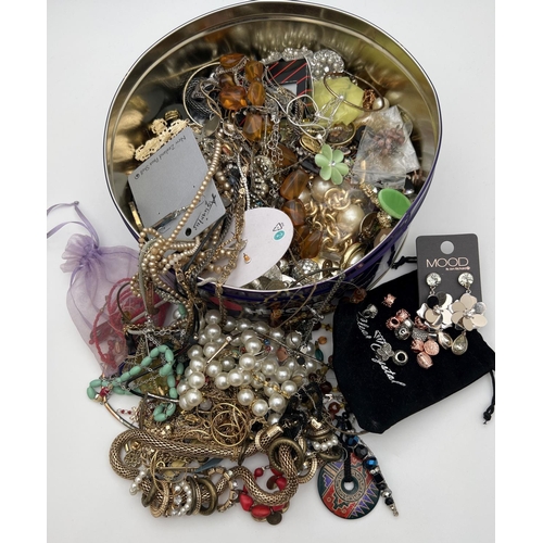 255 - A tin of assorted vintage and modern costume jewellery to include necklaces, earrings, pendants, rin... 