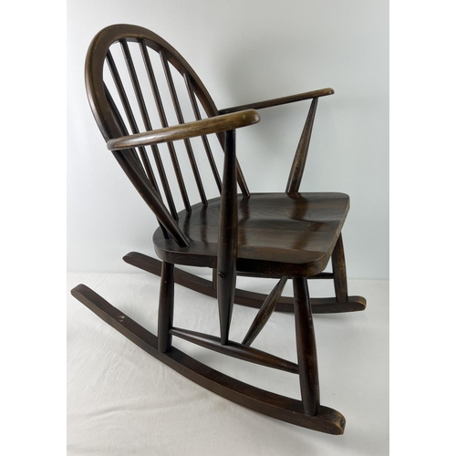 A mid century Ercol dark wood child's rocking chair with looped spindle design back. With blue square shaped transfer and impressed mark to back of seat. Seat looks to have been re-glued at some point. In solid good condition.