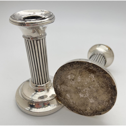 1115 - A pair of early 20th century silver covered candlesticks with chanelled design stems and stepped fee... 