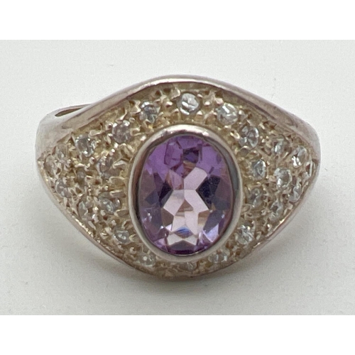 1016 - A silver, amethyst and cubic zirconia dress ring with central bezel set oval cut amethyst. Set with ... 