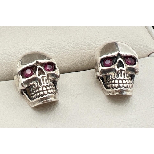 1023 - A pair of silver skull shaped stud earrings set with rubies. Reverse of earrings and butterfly backs... 