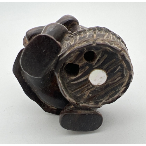 1212 - A carved wooden netsuke modelled as a man stirring a pot. Set with small mother of pearl disc to und... 