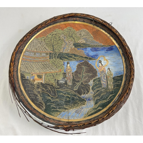 1219 - A large Oriental hand painted plate with wicker weaved frame (a/f). Blue & white painted detail to u... 