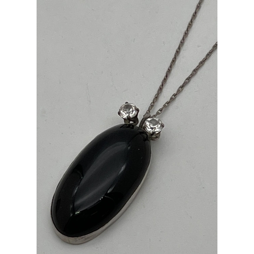 1041 - An oval shaped pendant set with black onyx, with 2 round cut clear stones to top. On an 18