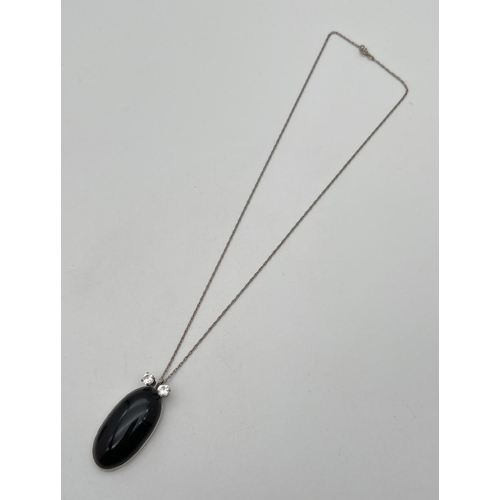 1041 - An oval shaped pendant set with black onyx, with 2 round cut clear stones to top. On an 18