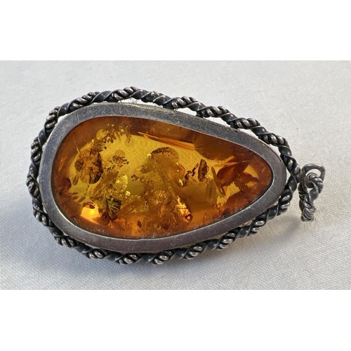 1056 - A large cognac amber pendant with a silver rope design mount and bale. Silver marks to bale. Pendant... 
