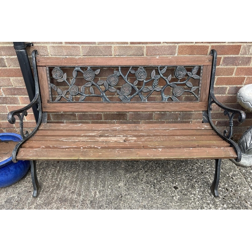 1479 - A modern wooden slatted garden bench with cast iron ends and back panel of floral design. Approx. 12... 