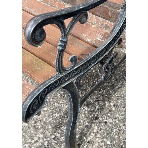 1479 - A modern wooden slatted garden bench with cast iron ends and back panel of floral design. Approx. 12... 