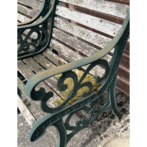 1488 - A pair of slatted wood garden seats with cast iron ends, painted green, with scroll detail. Each app... 