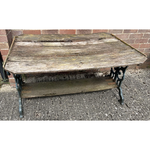 1493 - A vintage wooden slatted garden table with cast iron ends, painted green, with scroll design. Wood s... 