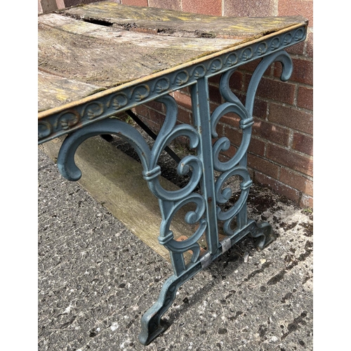 1493 - A vintage wooden slatted garden table with cast iron ends, painted green, with scroll design. Wood s... 