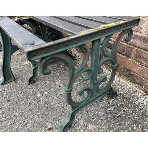 1512 - A wooden slatted garden seat and matching footstool/side table, with cast iron ends. Painted green w... 