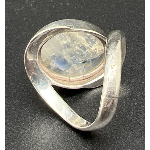 1105 - A modern design silver dress ring with twist style mount  set with a large moonstone cabochon. Silve... 