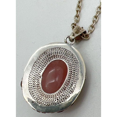 1051 - An oval shaped silver filigree style pendant set with a rose quartz cabochon, on an 18