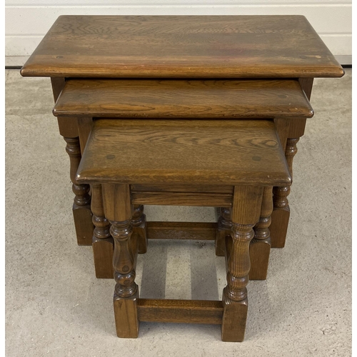 1423 - A vintage solid oak nest of 3 tables with turned design splayed legs. Approx. 45cm tall x 60cm long.