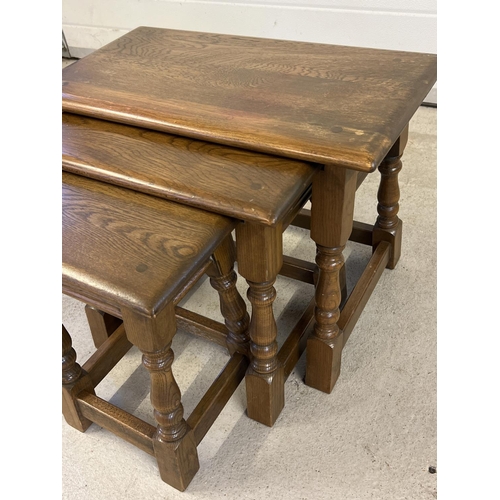 1423 - A vintage solid oak nest of 3 tables with turned design splayed legs. Approx. 45cm tall x 60cm long.