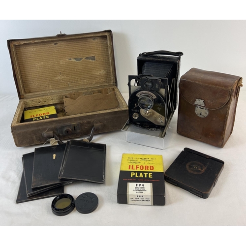 An antique Newman & Guardia New Ideal Sybyl folding camera in original leather case. Complete with original plate cases, 2 boxes of vintage plates, a cased Omag 32 filter and tripod board. Comes in a small adapted vintage suitcase.
