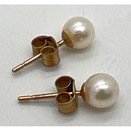 1061 - A pair of 9ct gold pearl stud earrings, with butterfly backs. Marks 9ct to backs. Total weight appro... 