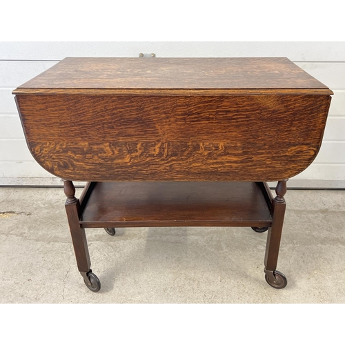 1430 - A vintage 1940's dark oak drop leaf tea trolley with turned legs and undershelf.