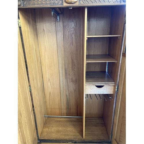 1442 - A vintage 1930's oak gentleman's wardrobe with beaded and carved detail to front. Interior has pull-... 