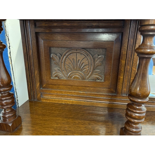 1445 - An Edwardian dark oak mirror backed side board with decorative carved columns and panelled detail. B... 