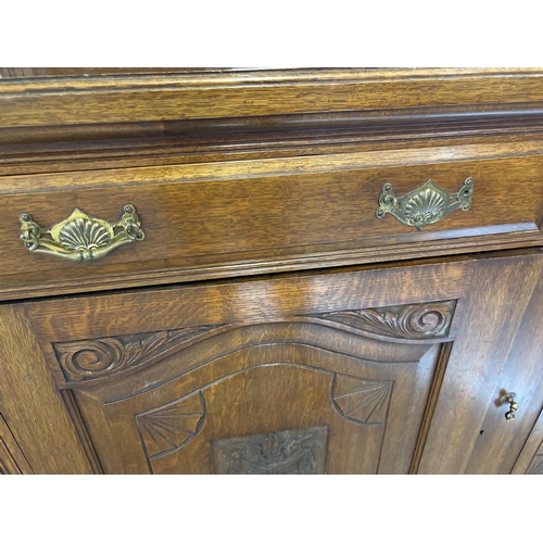 1445 - An Edwardian dark oak mirror backed side board with decorative carved columns and panelled detail. B... 