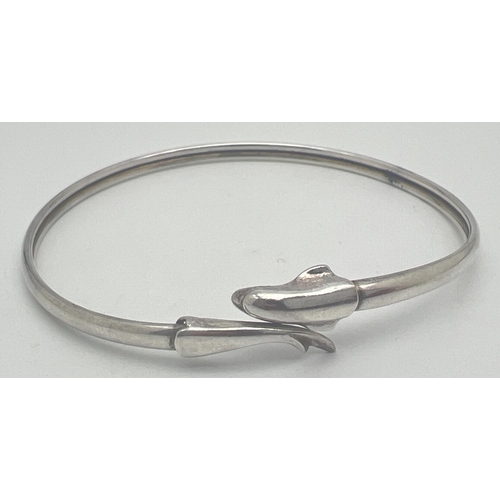 1078 - An adjustable silver bangle with dolphin detail. Marked Silver to inside. Approx. 7cm diameter. Tota... 