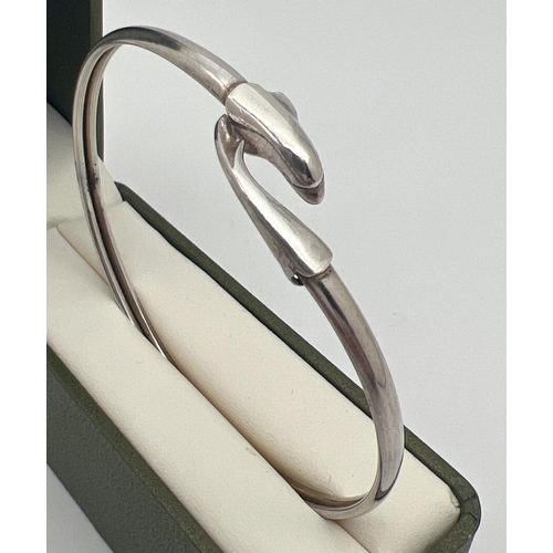 1078 - An adjustable silver bangle with dolphin detail. Marked Silver to inside. Approx. 7cm diameter. Tota... 