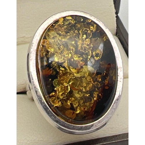 1080 - A large modern design silver dress ring set with an oval green amber cabochon. Silver mark to outsid... 