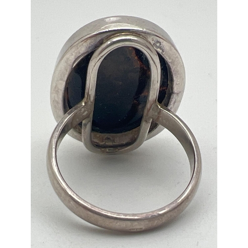 1080 - A large modern design silver dress ring set with an oval green amber cabochon. Silver mark to outsid... 