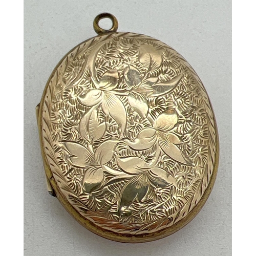 1084 - A yellow metal (front and back) oval locket with floral decoration to front and foliate & scroll eng... 