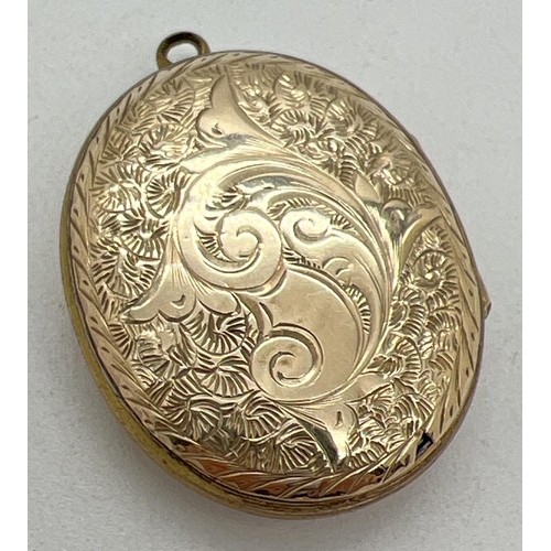 1084 - A yellow metal (front and back) oval locket with floral decoration to front and foliate & scroll eng... 