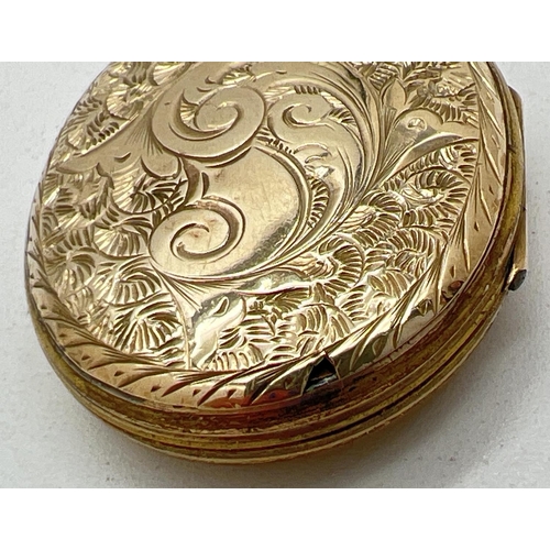 1084 - A yellow metal (front and back) oval locket with floral decoration to front and foliate & scroll eng... 