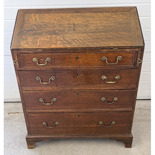 1424 - An antique oak 4 drawer bureau with internal stationery compartments and brass drop down handles. Ap... 