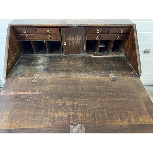 1424 - An antique oak 4 drawer bureau with internal stationery compartments and brass drop down handles. Ap... 